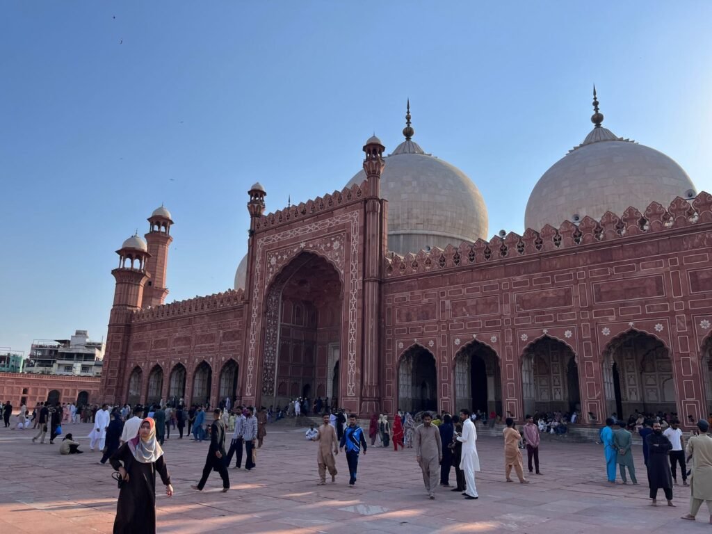 A bustling afternoon at the historic Badshahi Mosque in Lahore with visitors exploring its grand architecture.